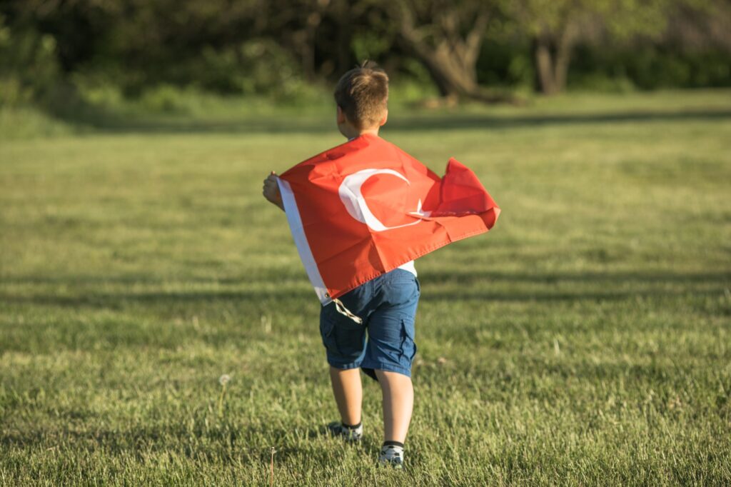 Boy holding Turkey flag. Kid hand waving Turkish flag view from back, copy space for text